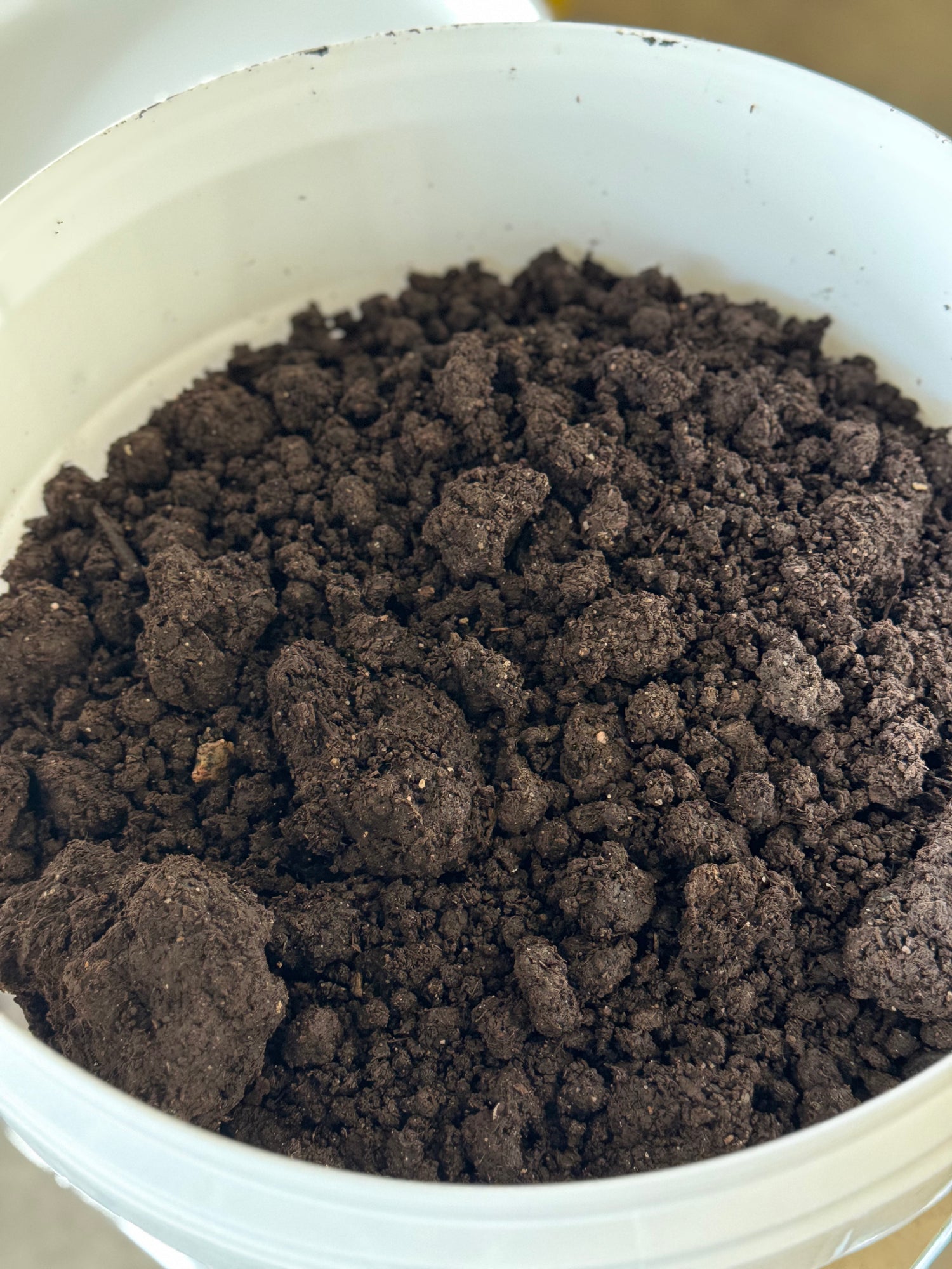 Bucket filled with worm castings on a neutral background